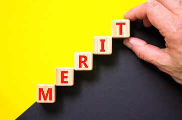 Merit symbol. Concept word Merit on beautiful wooden blocks. Beautiful yellow and black background. Businessman hand. Business lifestyle merit concept. Copy space.