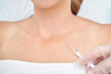 Female receiving cosmetic treatment with injection to neck area in medical spa setting.
