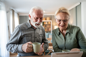 Older couple spending time together with coffee and tablet