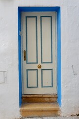 Fototapeta premium White weathered door with blue frame in Peniscola, Spain