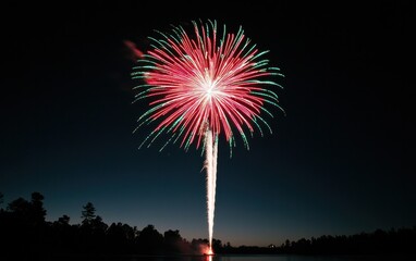 Vibrant Red and Green Fireworks Display Over Dark Water at Night