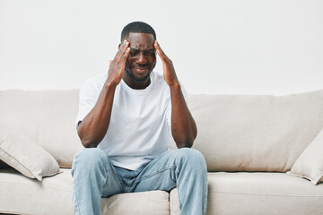An African American man in casual clothing shows frustration while sitting on a couch, highlighting the theme of stress and mental health