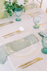 Transparent plates on green napkins stand on the festive table