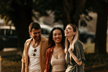 Group of Friends embraced playfully walking across a pedestrian crossing, full of laughter.