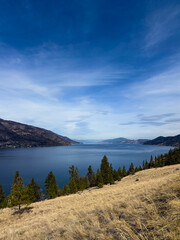 Okanagan lake and surrounding mountains under a blue sky on a late winter day