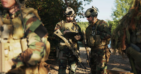 The military prepares for a field exercise as soldiers in camouflage uniforms with rifles and...