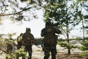Fototapeta premium Soldiers dressed in moro uniforms, marching in a line with guns in hand, monitor the terrain, patrol the area, and engage in border security drills while training on the firing range.