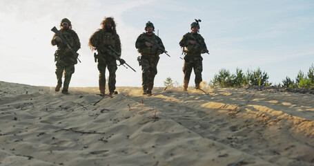 Military personnel, fully equipped with helmets and rifles, leave the observation post after...