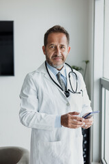 portrait of senior latin man doctor using phone at office or hospital in Mexico Latin America