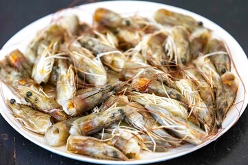 Fresh shrimps on white round plate isolated in selective focus. Shrimp head
