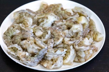 Fresh shrimps on white round plate isolated in selective focus. Shrimp head