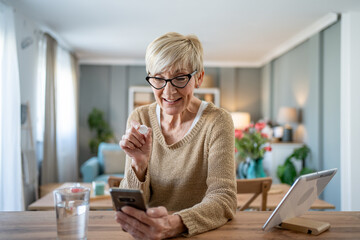 Senior woman dissolving an effervescent tablet in water while having a video call with her doctor