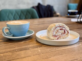 A Delightful and Delicious Coffee Alongside an Amazing Dessert Experience Awaiting You. A beautifully crafted latte alongside a delicious pastry resting on a warm wooden table, ideal for cafe goers