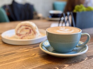 A Delightful and Delicious Coffee Alongside an Amazing Dessert Experience Awaiting You. A beautifully crafted latte alongside a delicious pastry resting on a warm wooden table, ideal for cafe goers