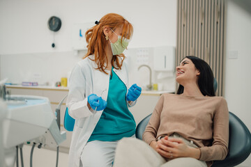 Female dentist wearing surgical mask talking to patient in dental clinic