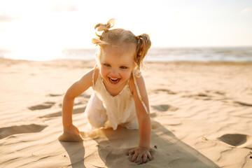 Happy little girl having fun on the beach on a sunny day. Beautiful child spending time together outdoors. Childhood, fun concept.