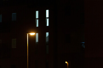 Fototapeta premium A street light is brightly lit up in front of a large building during the night, illuminating the surroundings with its warm glow