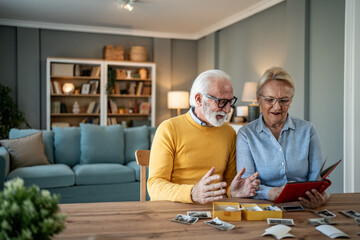 Senior couple watching old photo albums and remembering memories at home