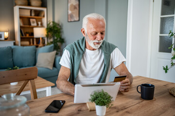 Senior man making online payment using tablet and credit card at home