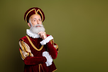 Elegant senior man in royal costume reflecting counterpose on a khaki background