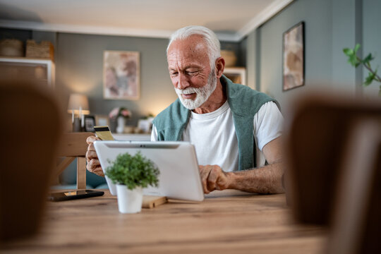 Senior man using digital tablet and credit card for online shopping at home