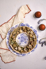 Easter table decor quail eggs on a blue plate on a blue background, top view