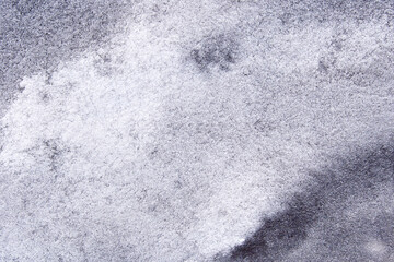 Abstract textured surface with gray and white patterns in natural lighting.