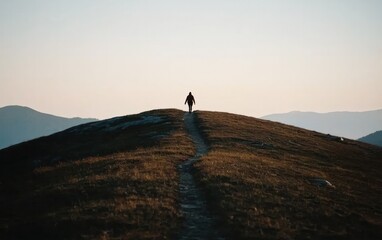 Person Walking on Hilltop Path at Sunrise