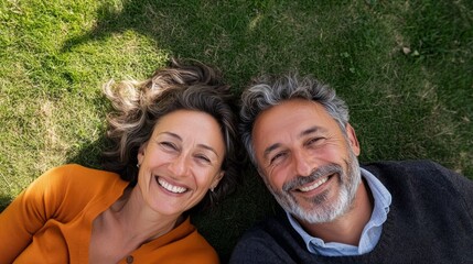 Fototapeta premium A happy middle age couple lying on the green grass together outdoors in the park.