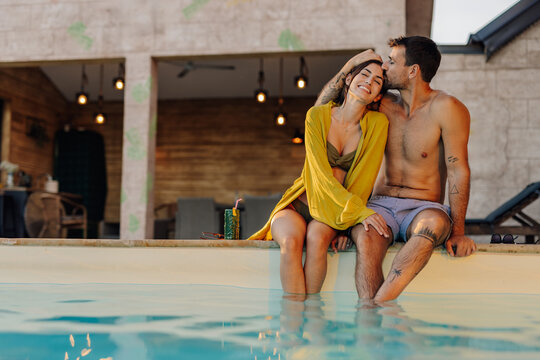 Happy couple kissing and relaxing by the pool during summer vacation