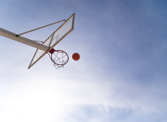 Basketball ball entering hoop on outdoor court on sunny day