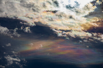 Sky photo featuring a mesmerizing pearl cloud beneath white clouds, with the sun hidden behind...