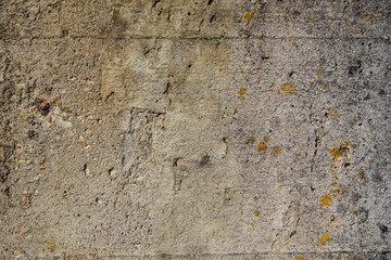 Close-up of a cement wall with rust spots, small cracks, and holes, showcasing texture and weathered details