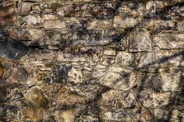 Old stone wall from 1800s Norwegian church ruins, weathered and textured, with tree branch shadows adding depth, ideal for background and texture