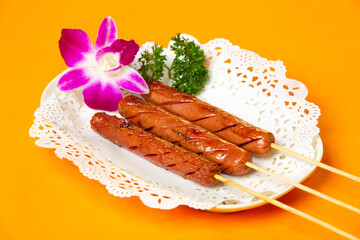 Grilled Chicken Sausage on Skewers served in plate isolated on orange background side view of hong kong food