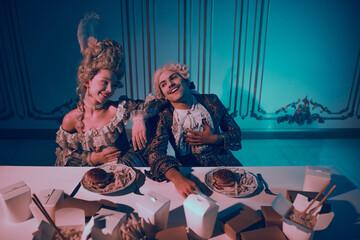 A vintage-themed couple in noble costumes enjoying a modern meal under neon lighting