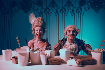Luxurious couple enjoying a modern meal in vintage costumes blending historical theme with...