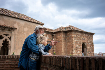 Grandfather and granddaughter enjoying a moment together, looking out over a historical stone wall...