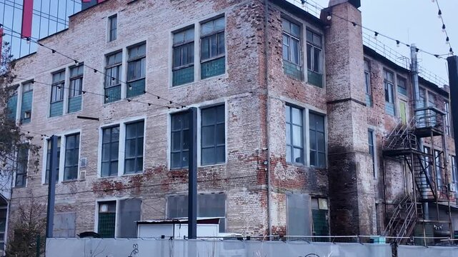 An old abandoned factory with damaged walls on the background of modern structures in the same area