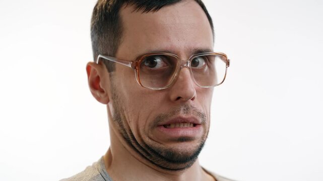 Man in glasses cringes with embarrassment at awkward moment