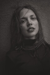 Black and white photos of a beautiful girl in a stylish short dress with her hair fluttering back poses on a terrace