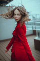 beautiful girl in red dress with waving back hair posing on the terrace