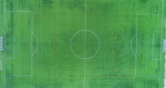 Zenithal top down aerial drone view of the centre of a football soccer pitch with players training
