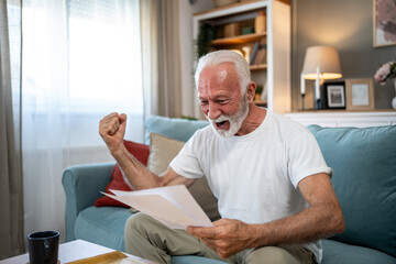 Fototapeta premium Excited senior man celebrating good news reading letter at home