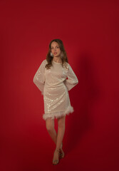 Beautiful girl in white dress in 70s style poses in studio on red background