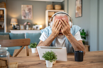 Senior man feeling frustrated while using digital tablet at home