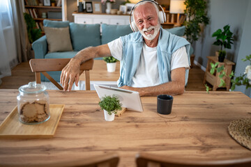 Senior man enjoying music and using tablet at home
