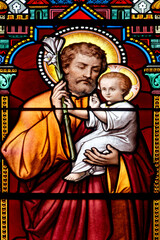Fototapeta premium Stained glass (19th century) of Saint Joseph holding baby Jesus Christ in his arms.