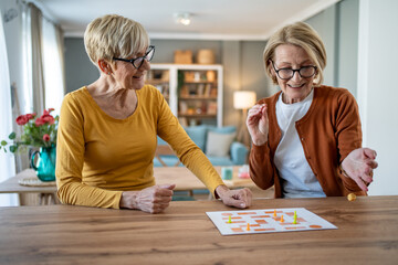Two senior women playing board games at home