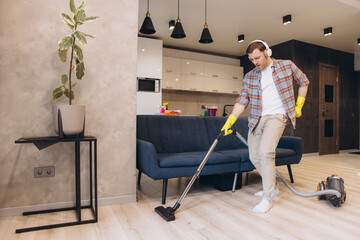 Man listening music and vacuuming living room floor